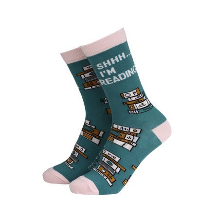 
"Eco-friendly teal bamboo socks by Smiling Faces, featuring playful stacked book designs and the slogan 'Shhh… I'm Reading'. Accented with soft pink heels, toes, and cuffs, perfect for book lovers, available at Rebel Romance.