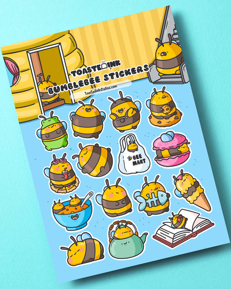 Angled shot of the Toastedink Bumble Bee Sticker Sheet on a light turquoise background. The sticker sheet displays adorable bees in funny and creative costumes such as a frog, teacup, fish, macaron, and ice cream. Ideal for bullet journalling, planner decorating, or scrapbooking.