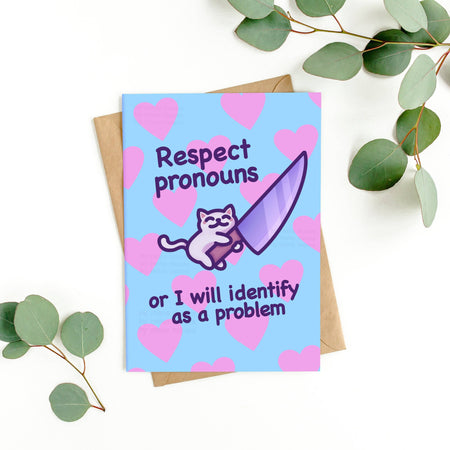 Humorous “Respect Pronouns” card by Mona Mauve for Rebel Romance placed on a white background with eucalyptus and kraft envelope. Features a white cartoon cat hugging a purple knife with pink hearts and bold supportive LGBTQIA+ text on a blue background.