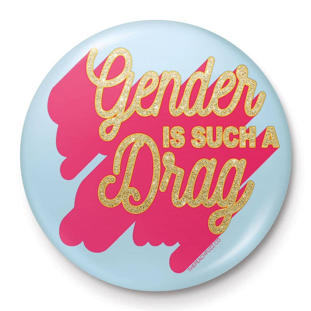 A 25mm round lapel pin with a light blue background and a vibrant pink splash design. The text “Gender Is Such A Drag” is written in glittery gold, combining humour and boldness in a compact accessory.