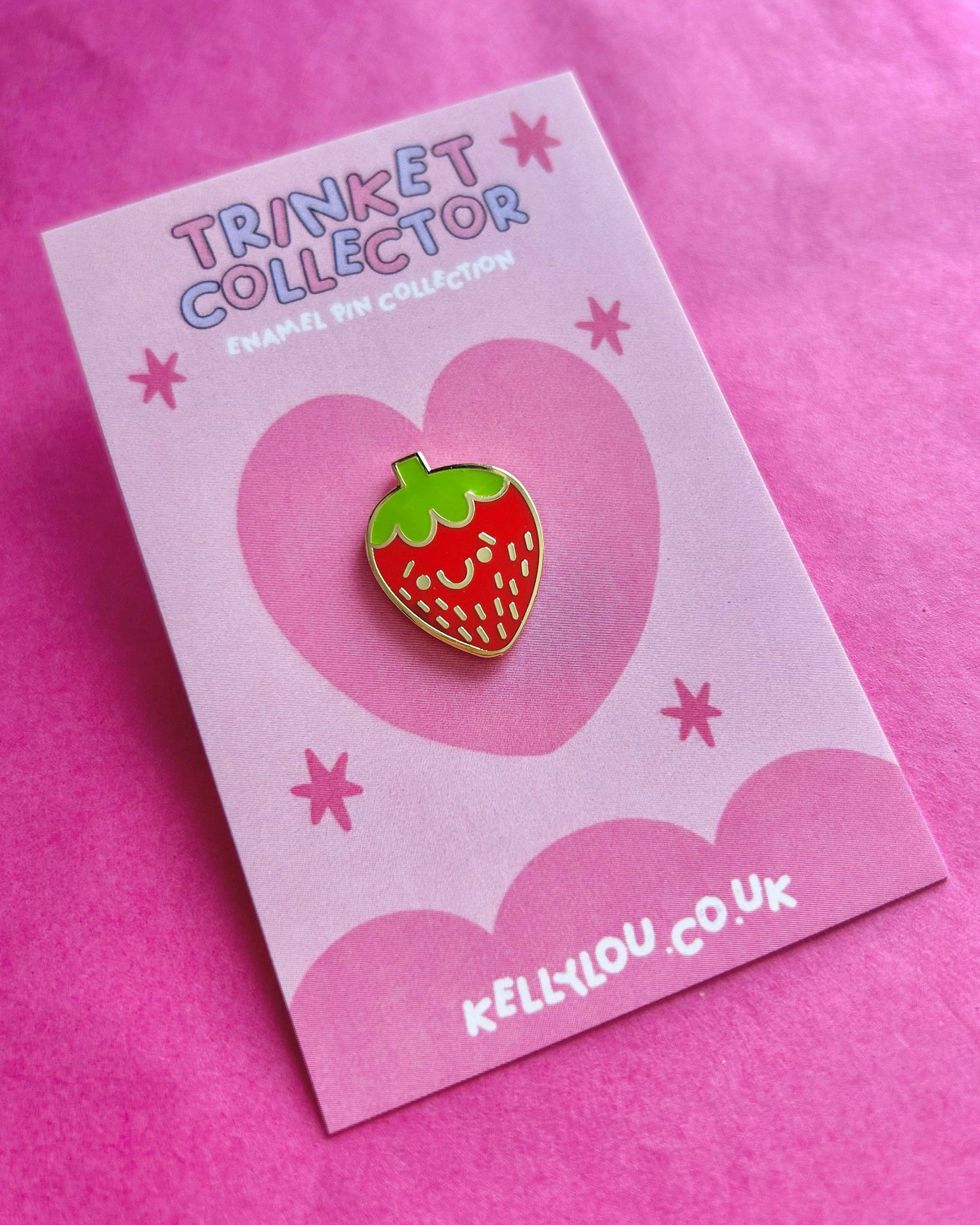 Berry Cutie Strawberry Mini Enamel Pin by Kelly Lou displayed on a pink heart-themed backing card against a bright pink background. Available from Rebel Romance, a UK small business offering fun alternative gifts, jewellery and slow ethical fashion for millennials.