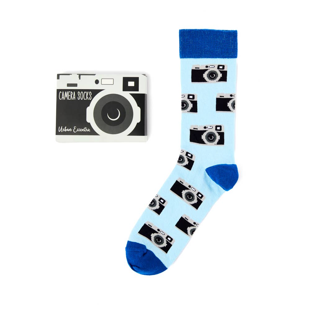 Urban Eccentric camera socks with vintage camera design on pale blue background, shown alongside novelty camera-shaped packaging. Available at Rebel Romance.
