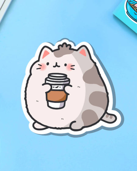 Close-up of the Coffee Cat Vinyl Sticker by Toastedink, sold by Rebel Romance. Features an adorable round cat with pink cheeks holding a coffee cup. High quality waterproof vinyl with a glossy finish, perfect for personalising tech and stationery.