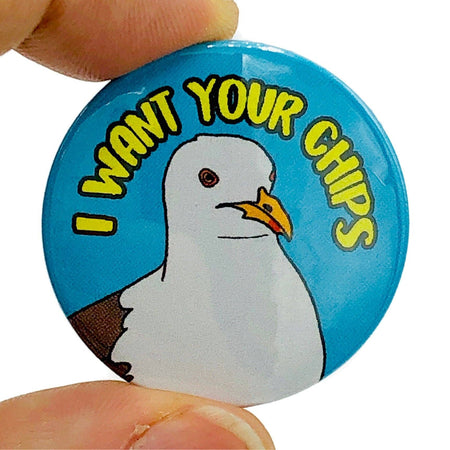 A 38mm glossy pin badge featuring a cheeky illustrated seagull on a bright blue background with bold yellow text that reads “I Want Your Chips.” A humorous and playful accessory celebrating British seaside culture.