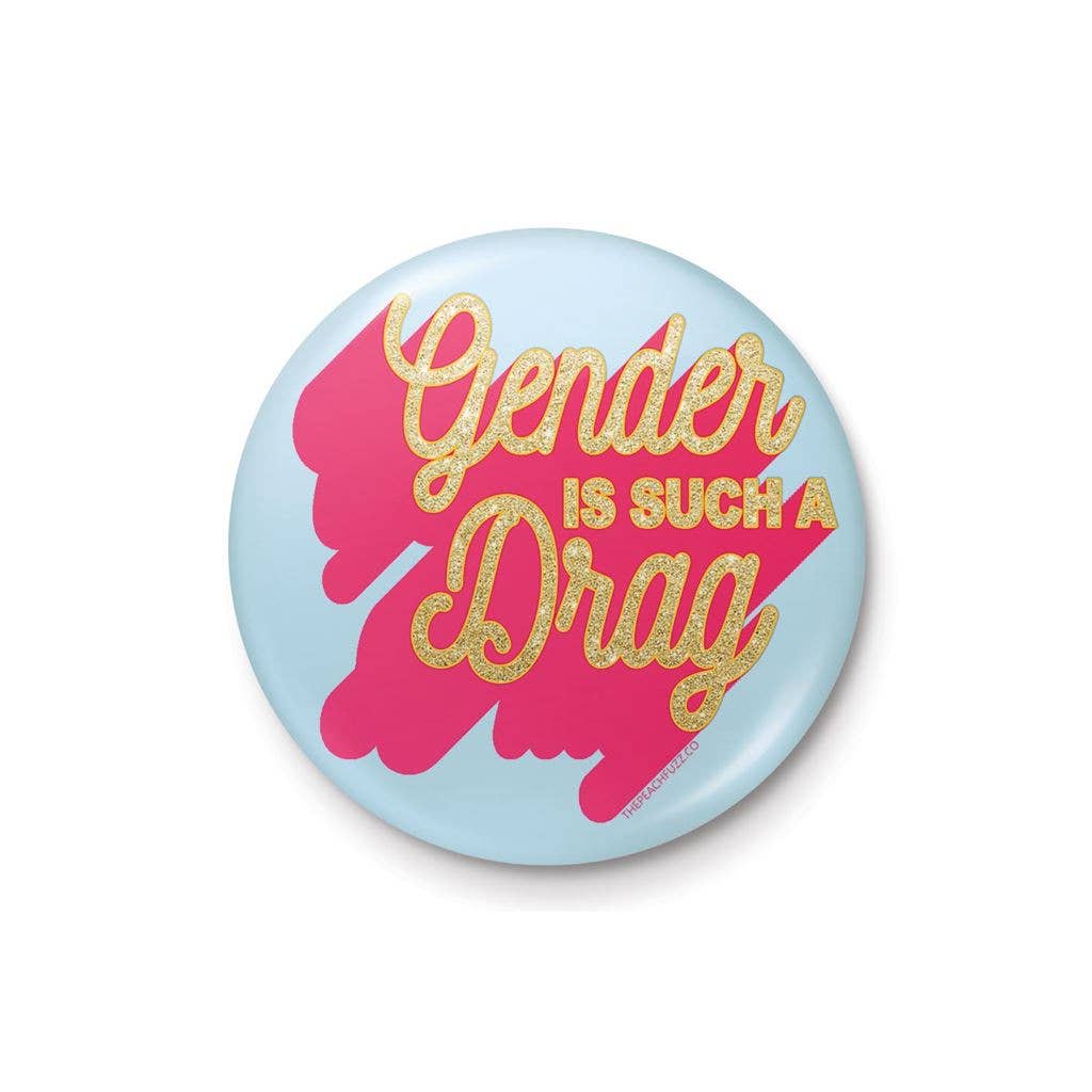 A 25mm round lapel pin with a light blue background and a vibrant pink splash design. The text “Gender Is Such A Drag” is written in glittery gold, combining humour and boldness in a compact accessory.