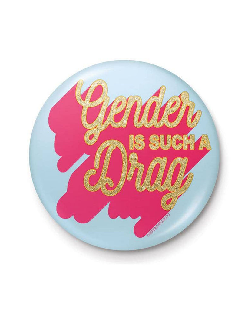 A 25mm round lapel pin with a light blue background and a vibrant pink splash design. The text “Gender Is Such A Drag” is written in glittery gold, combining humour and boldness in a compact accessory.