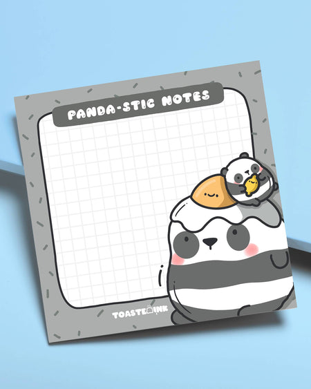 Flat lay of Toastedink's Panda-stic Notes sticky pad on a blue background. Featuring a chubby panda with a sunny-side-up egg and baby panda chick, available at Rebel Romance – a UK small biz for millennial magic lovers.