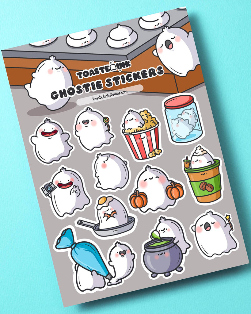 Toastedink ghostie sticker sheet featuring cute ghost characters doing funny activities like eating popcorn, sitting in a plant pot, and hiding in a piping bag. Displayed on a turquoise blue background. Sold by Rebel Romance, a UK brand celebrating alternative, kawaii stationery.
