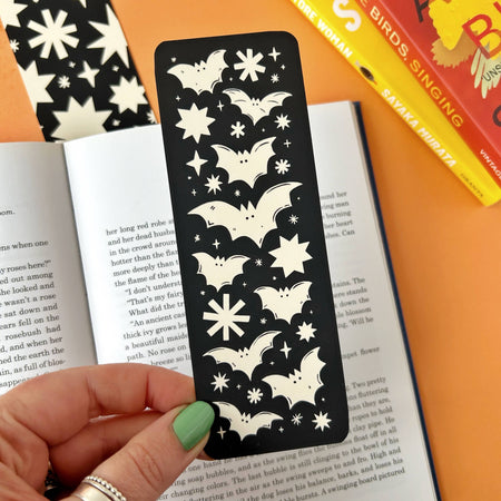 Discover the Bats Bookmark – a gothic Halloween-inspired accessory featuring a spooky bats and stars design by Stacey McEvoy Caunt. Luxurious velvet matte finish, 14.8 x 5.2 cm, and professionally printed in the UK. Perfect for book lovers and spooky season enthusiasts!