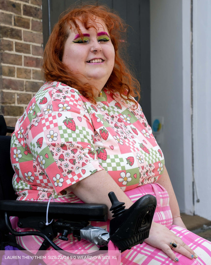Person with red hair wearing a colorful outfit sitting in a wheelchair.