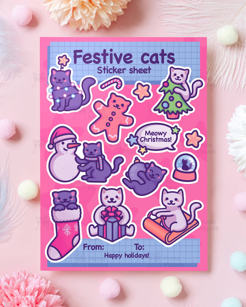 A styled flatlay of the Christmas Festive Cats Sticker Sheet by Rebel Romance decorated with fluffy pom poms and pastel flowers. The A5 vinyl sheet features Mona Mauve festive cat illustrations including gift giving cats, fairy light cats, a snow globe and seasonal icons. The bright pink and purple palette adds playful holiday charm for millennial stationery lovers.