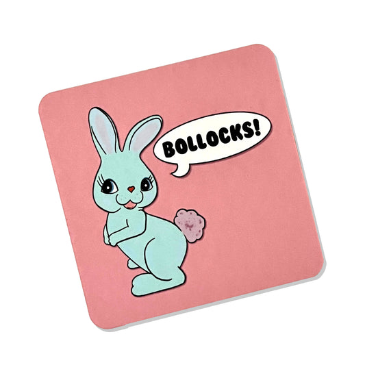 Square pink drinks coaster by Rebel Romance featuring a kitsch turquoise bunny with a pink fluffy tail saying “Bollocks!” in a comic-style speech bubble. Designed by Bite Your Granny, this cheeky and colourful homeware item blends vintage charm with bold swearing, ideal for adding personality to your table. A fun gift for anyone with a love of quirky, alternative aesthetics.