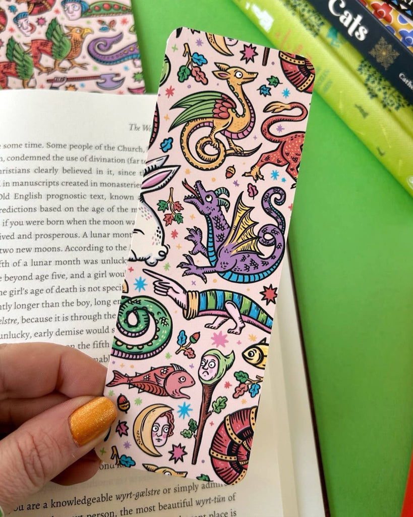 An aesthetic pastel bookmark covered in whimsical medieval creatures including dragons, moons, snails, and strange plants. Designed by Stacey McEvoy Caunt, this double-sided bookmark is sold by Rebel Romance, an alternative UK indie brand.