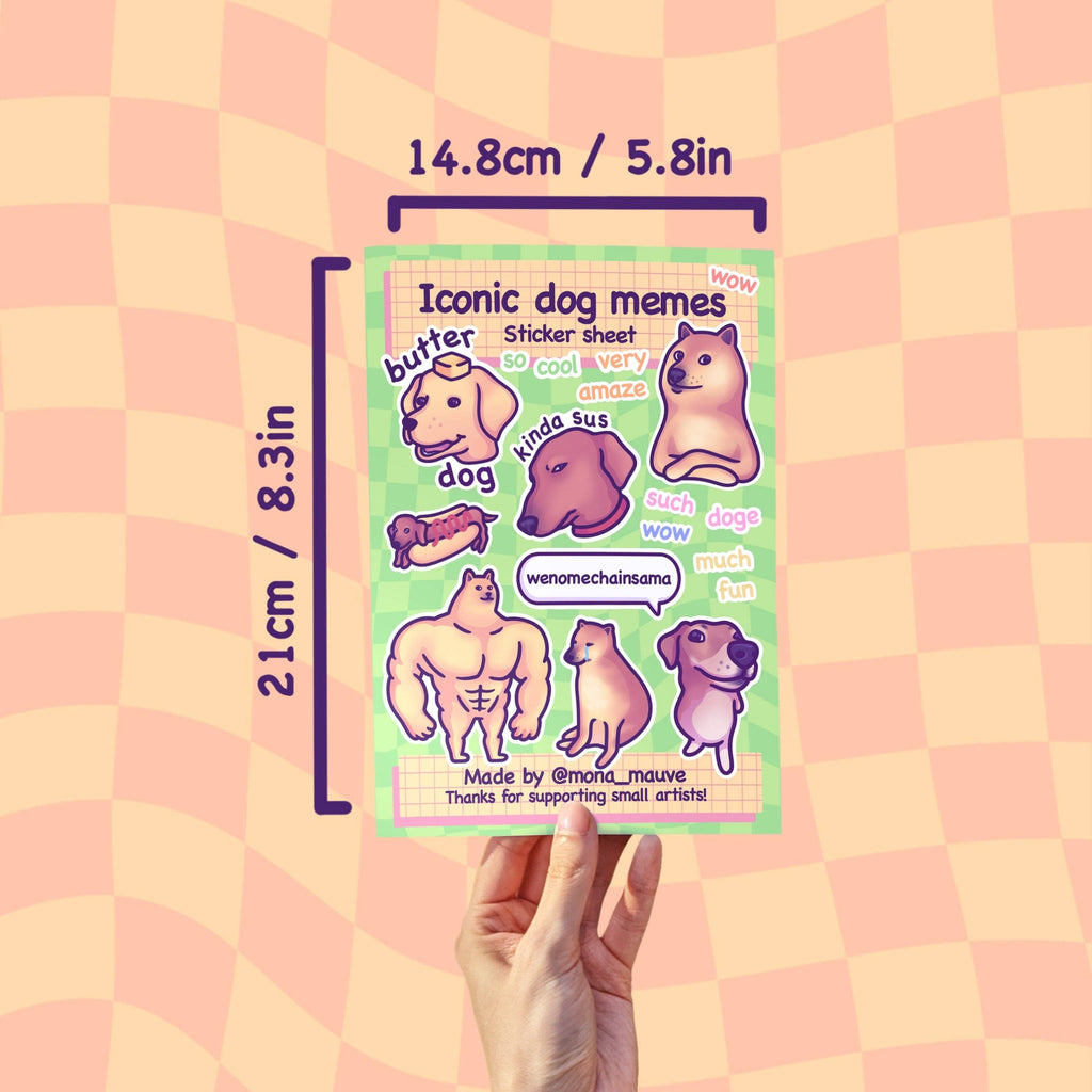 A hand holds the Iconic Dog Memes Sticker Sheet by Mona Mauve against a peach checkerboard background, showing the size as 21cm by 14.8cm. The sheet includes 18 funny vinyl stickers with popular internet dog meme characters and quotes like “wow,” “so cool,” and “amaze.” A fun, bold stationery pick from an indie artist.