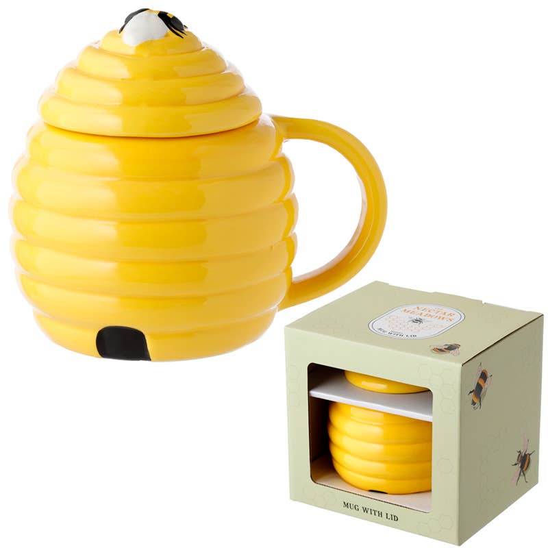 The beehive ceramic mug with lid is shown next to its gift box packaging. The box features the same beehive shape and yellow colour. A fun mug with a cottagcore style bee design from Rebel Romance.