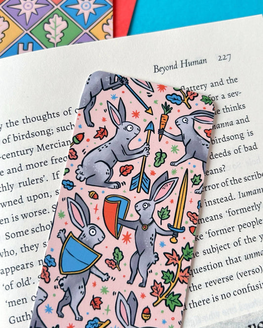 Detail view of the Medieval Rabbits Bookmark from Rebel Romance, showing armoured bunnies with swords, shields, trumpets, and arrows. The whimsical medieval-inspired design is filled with bright leaves, stars, and carrots.