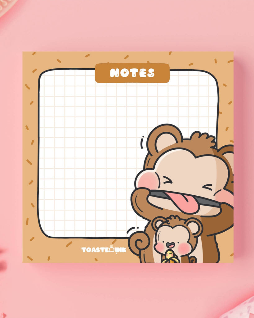 Toastedink monkey sticky notes on a soft pink background. Featuring two kawaii monkeys, one with a banana, and a cheerful grid design. Sold by Rebel Romance, a UK-based shop for cute and quirky gifts and stationery.