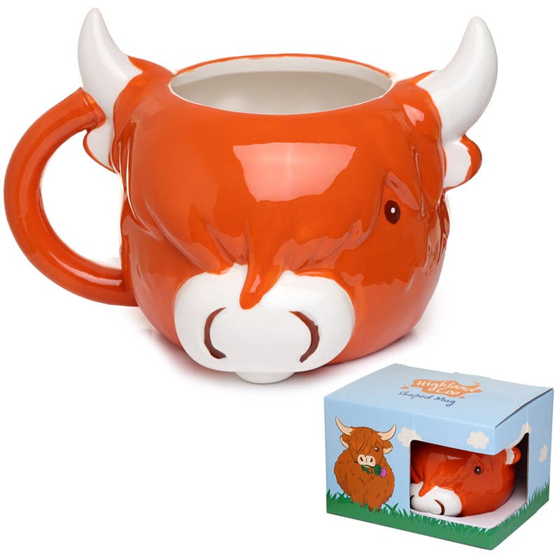 Front-facing image of the Highland Coo Mug next to its illustrated gift box. The mug features a white snout, fringe detail, and two cartoon eyes. A charming gift from Rebel Romance.