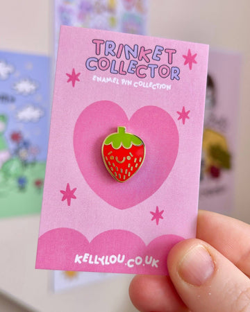 Close-up of the Berry Cutie Strawberry Mini Enamel Pin by Kelly Lou on a pink backing card with heart and star designs. Sold by Rebel Romance, a UK small business celebrating alternative style for millennials with quirky gifts, jewellery and ethical fashion.