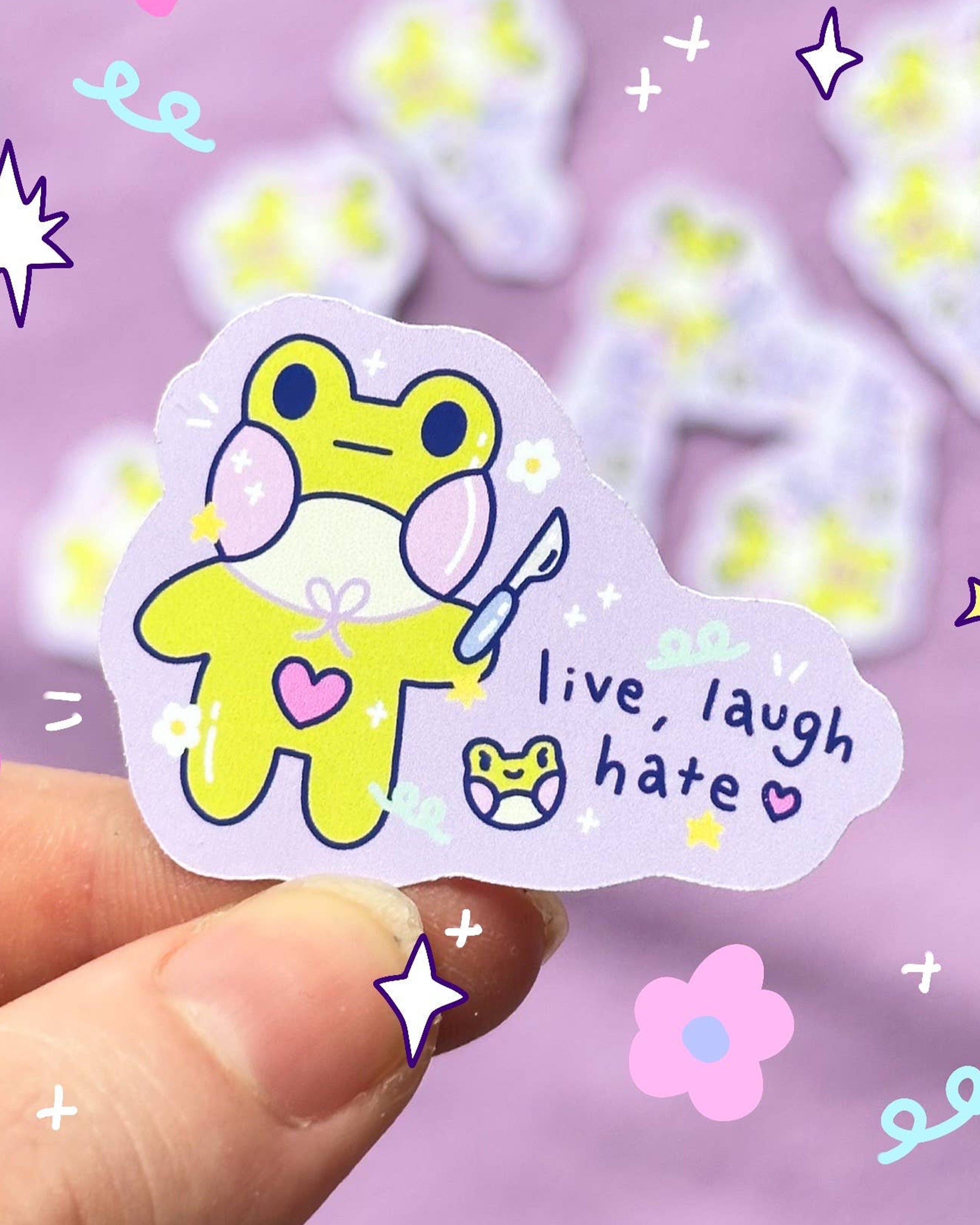 Cute handmade mini frog sticker by Sun Puff Studios, sold at Rebel Romance. Features a yellow pastel frog holding a scalpel with the text 