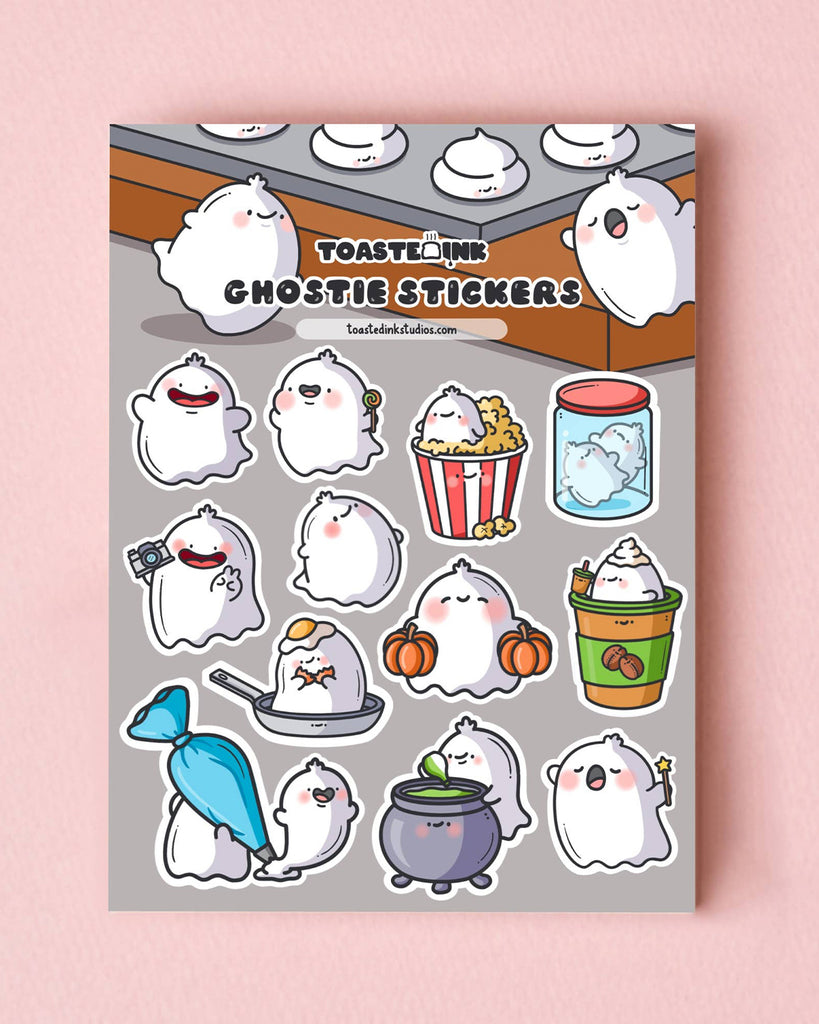 Ghostie sticker sheet by Toastedink shown flat on a pink backdrop, with a variety of adorable ghost characters – from ghosts sipping drinks to those in jars. Available at Rebel Romance, a quirky UK lifestyle and stationery shop.