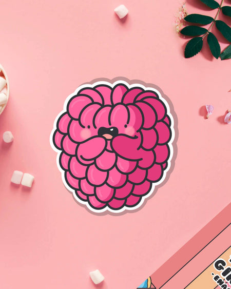 Cute raspberry vinyl sticker by Toastedink featuring a kawaii cartoon raspberry with a happy face and paws, photographed on a pink background with marshmallows. Stocked by Rebel Romance, a UK brand for alternative, retro and whimsical stationery lovers.