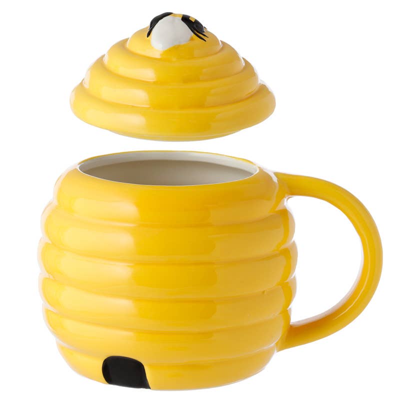 A yellow beehive-shaped ceramic mug with the lid floating above, revealing the inside. The lid features a 3D bee on top. Unique homeware from Rebel Romance, a UK indie brand.