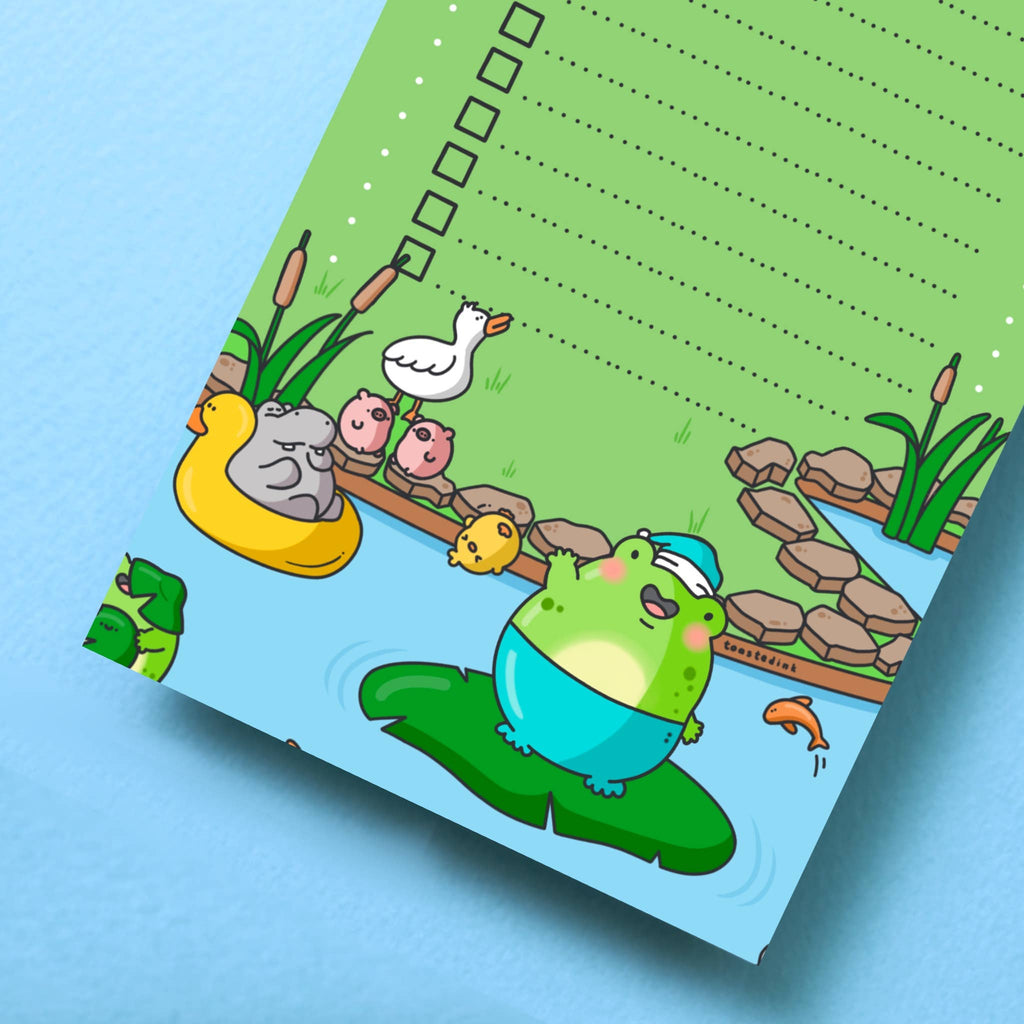 A green DL-sized to-do list pad titled “Un-froggetable things I need to do” with a checklist of dotted lines and tick boxes. The bottom features a cute cartoon frog in a blue floatie, sitting on a lily pad, surrounded by pond animals and plants. Perfect for fun and functional daily planning.