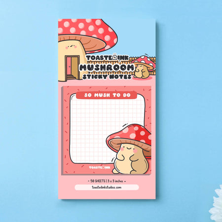 A square sticky note pad with a red border and grid paper design, featuring a cute, blushing mushroom character with a red and white spotted cap in the bottom right corner. The top header reads “So Mush To Do” in bold white text. A fun and functional memo pad for everyday reminders.