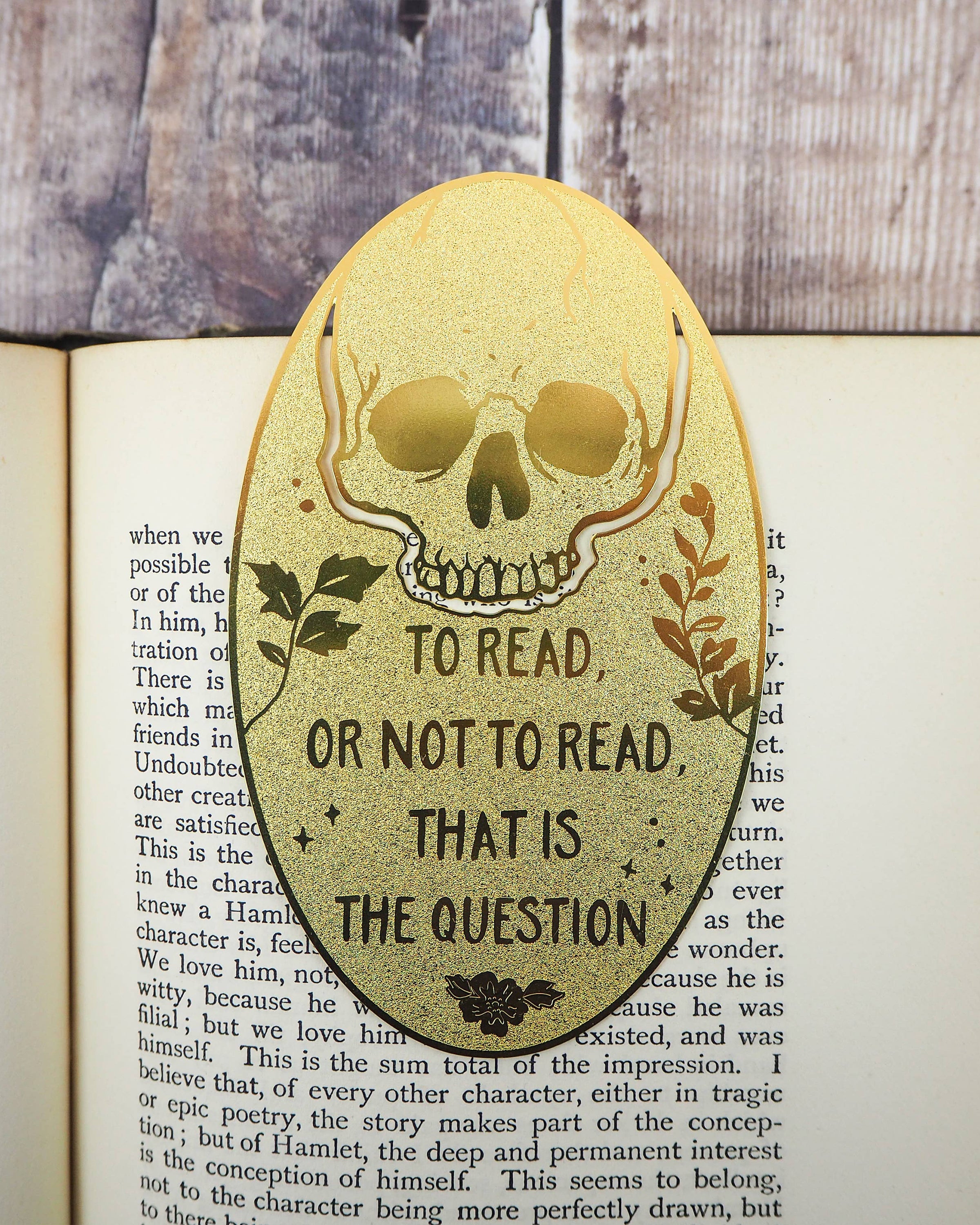 Engraved brass skull bookmark featuring “To read or not to read, that is the question” by Literary Emporium, shown in an open book. Sold by Rebel Romance, UK small business for unique alternative gifts.