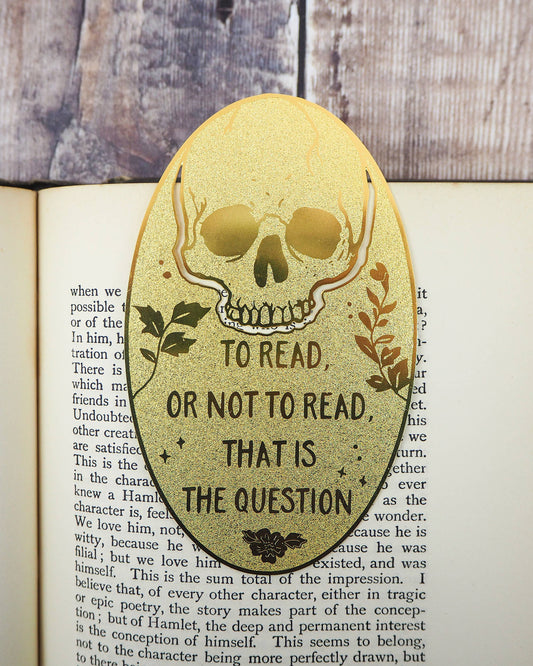Engraved brass skull bookmark featuring “To read or not to read, that is the question” by Literary Emporium, shown in an open book. Sold by Rebel Romance, UK small business for unique alternative gifts.