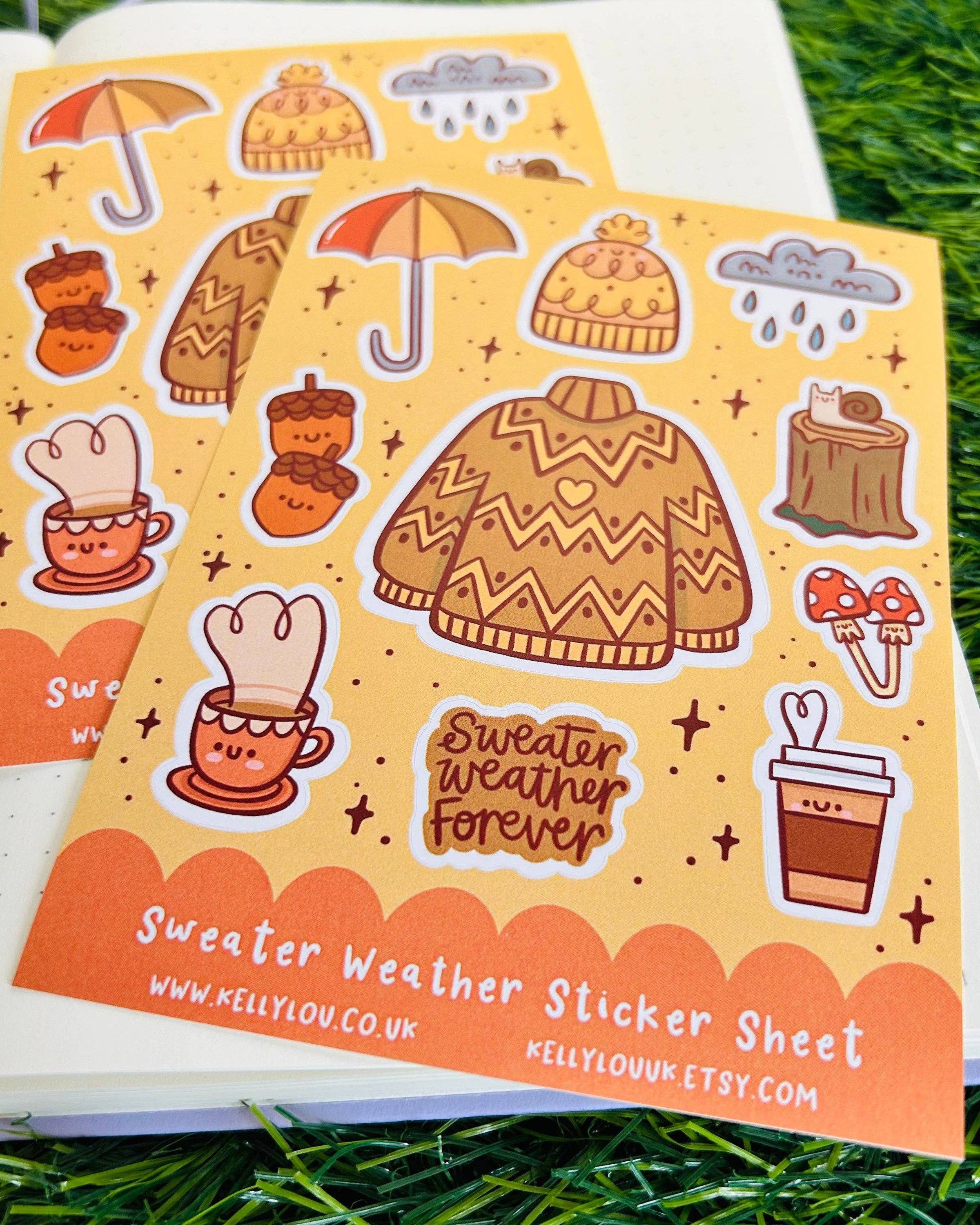Rebel Romance Sweater Weather Sticker Sheet by Kelly Lou displayed on a notebook with grass background. Features cute autumn illustrations including a knitted jumper, umbrella, hat, mushrooms, hot drink, and the phrase “Sweater Weather Forever.” A6 waterproof matte vinyl sticker sheet perfect for scrapbooking, bullet journaling, or autumn-themed gifts.