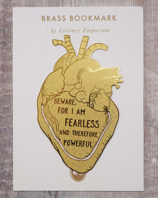 A gold brass anatomical heart-shaped bookmark engraved with the quote “Beware; for I am fearless and therefore powerful” from Mary Shelley’s Frankenstein. The bookmark is delicately etched with intricate vein details, resting on an open book to mark a page.