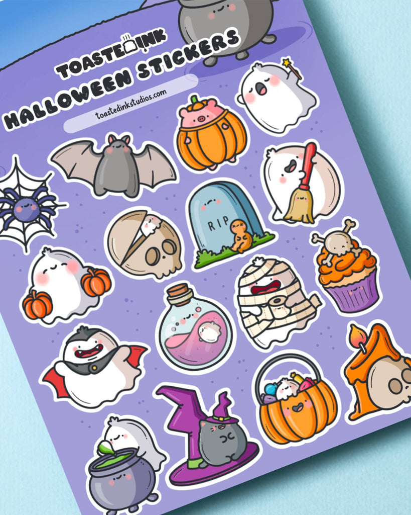Diagonal view of Toastedink Halloween stickers featuring a cauldron-stirring ghost, bats, pumpkins, gravestone, witch’s hat, and spooky sweets in a pastel purple design, ideal for stationery and crafts.