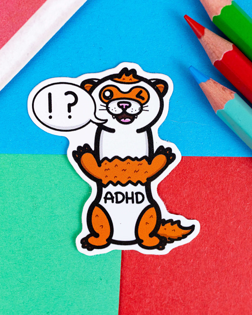 Illustrated ADHD vinyl sticker by Innabox, sold by Rebel Romance, a UK small business. The design features a cute cartoon ferret with the word “ADHD” on its tummy, winking with its tongue out and a speech bubble that reads “!?”. Brightly coloured background with red, blue, green, and coloured pencils. Fun way to raise ADHD awareness with a quirky, neurodivergent twist.