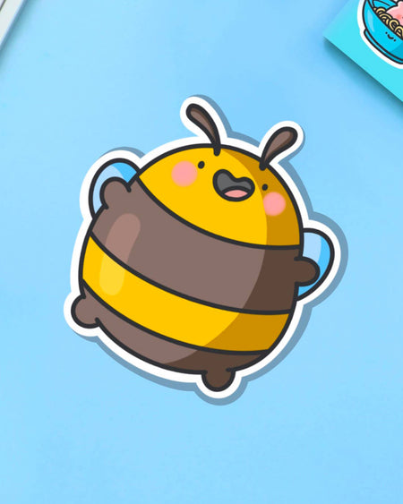 Glossy vinyl sticker of a round, cartoon-style yellow and brown bumblebee jumping happily with pink cheeks and arms raised. Displayed on a blue background. Fun and cute waterproof sticker, perfect for decorating laptops and notebooks.