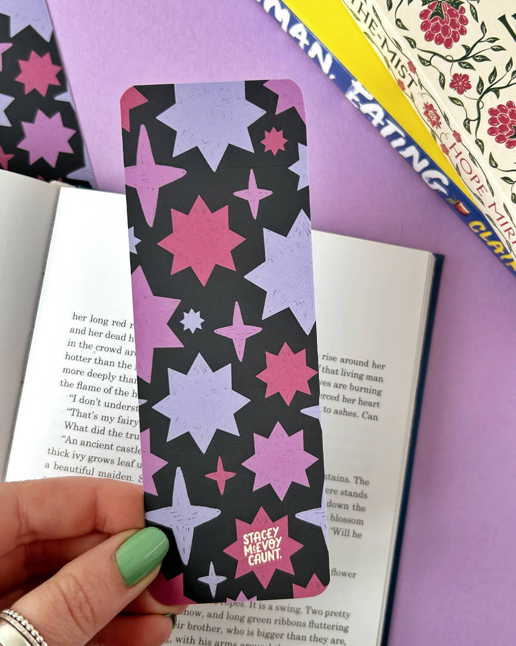 The reverse side of the bookmark showing a bold starry pattern in shades of pink, purple, and black, with “Stacey McEvoy Caunt” printed at the bottom.

