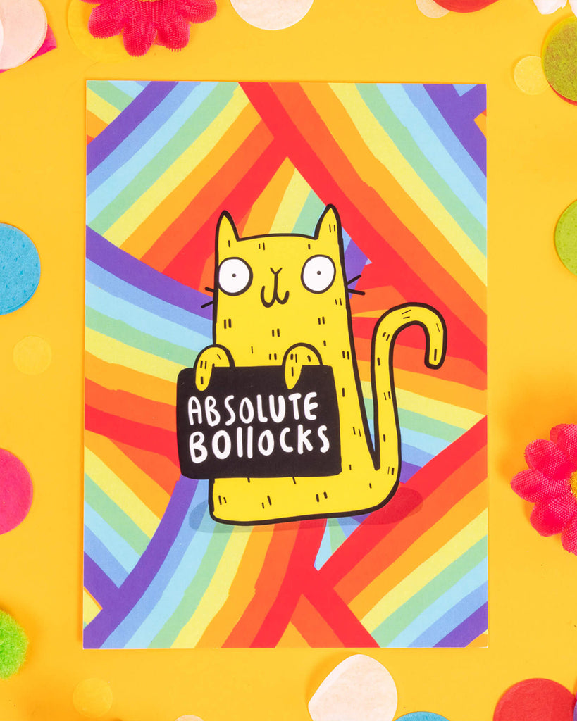 A vibrant A6 postcard featuring a cartoon yellow cat holding a sign that says “Absolute Bollocks” with a bold rainbow-striped background. Designed by Katie Abey, this sweary cat card is ideal for millennials who love colourful humour, alternative stationery, and no-nonsense messages delivered with style.