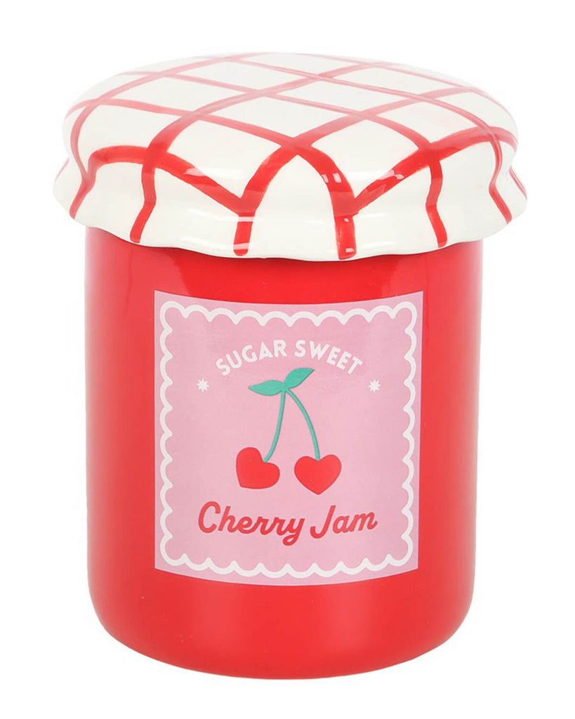 Close-up of the cherry jam jar oil burner with a glossy red ceramic body, a pastel pink label with two cherries, and a gingham-style red and white ceramic lid.