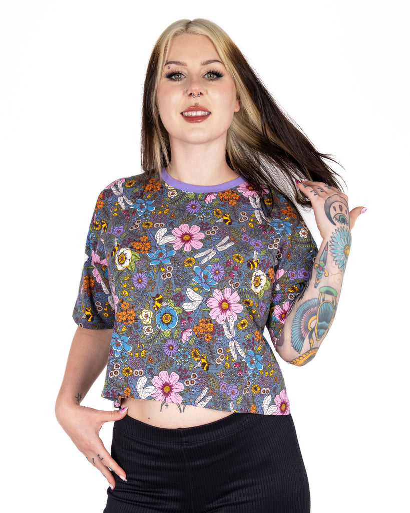 Florence flicks her hair while wearing the Rebel Romance Cottagecore Cropped Boxy Tee. The top has a boxy, cropped shape and all-over whimsical floral print, perfect for fans of romantic alternative style and slow fashion.