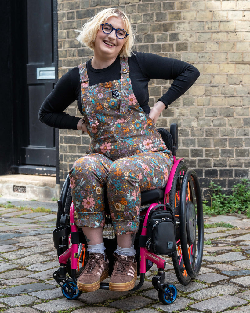 Eliza beams while modelling Rebel Romance’s Cottagecore Stretch Twill Dungarees in a charming floral woodland print. Styled with brown trainers and a black top, the look embraces comfort, style, and alternative fashion. Shot outdoors, proudly showcasing UK ethical brand Rebel Romance.