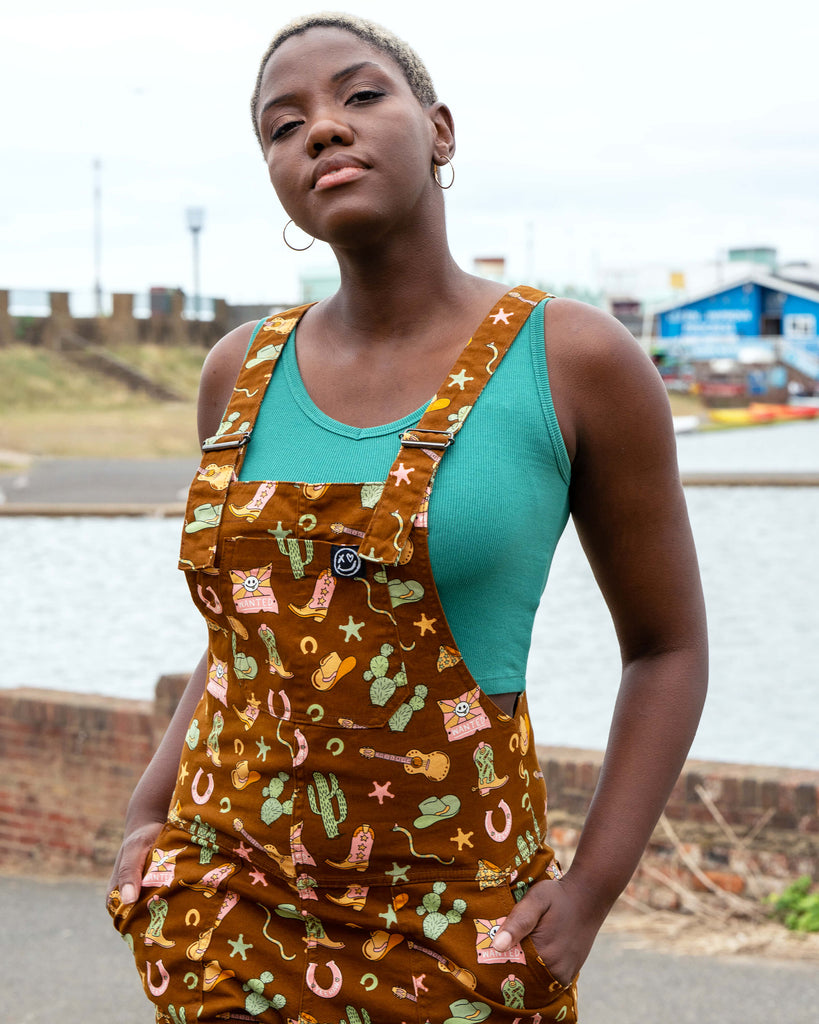 Front bib detail of Rebel Romance x Yasmin Cousins Cowboy Dungarees, showing pocket and all-over western-inspired print on brown stretch twill.