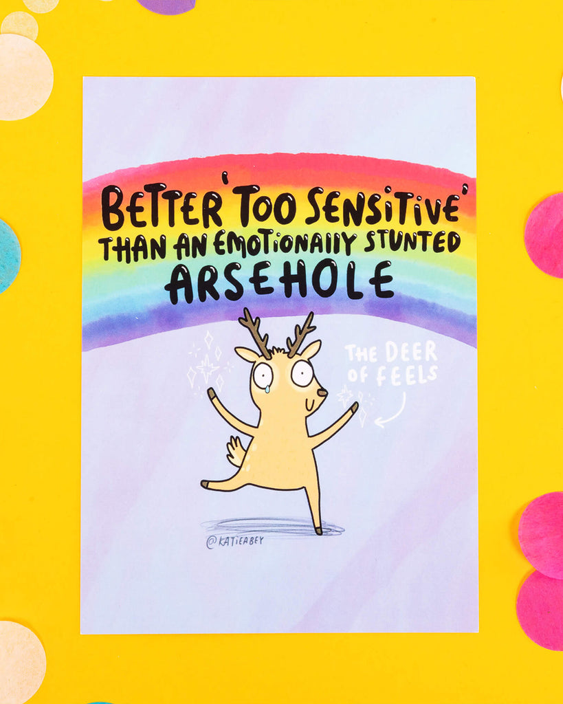 A colourful A6 postcard illustrated by Katie Abey featuring a cartoon deer under a rainbow with the text “Better ‘Too Sensitive’ Than An Emotionally Stunted Arsehole.” The deer is labelled “The Deer of Feels” and stands on a purple background. Fun, empowering, and full of personality.