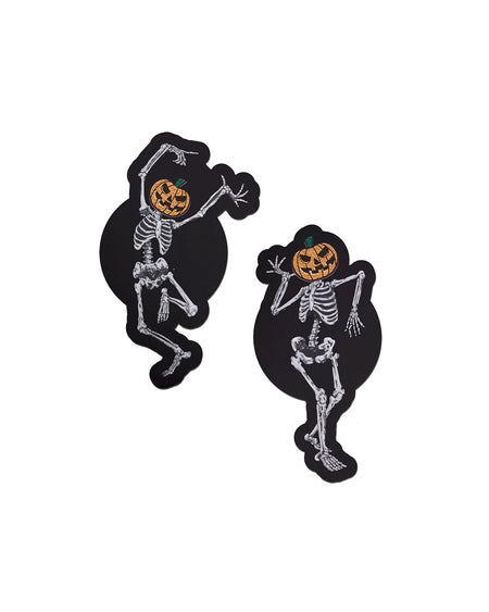 Dancing Skeletons Pasties with Pumpkin Heads Spooky Scary Skeletons nipple covers on a white background. One of the skeletons is dancing with one leg in the air and both arms up, while the other is dancing with arms bent and legs together. Both skeletons have orange spooky faced pumpkin heads.