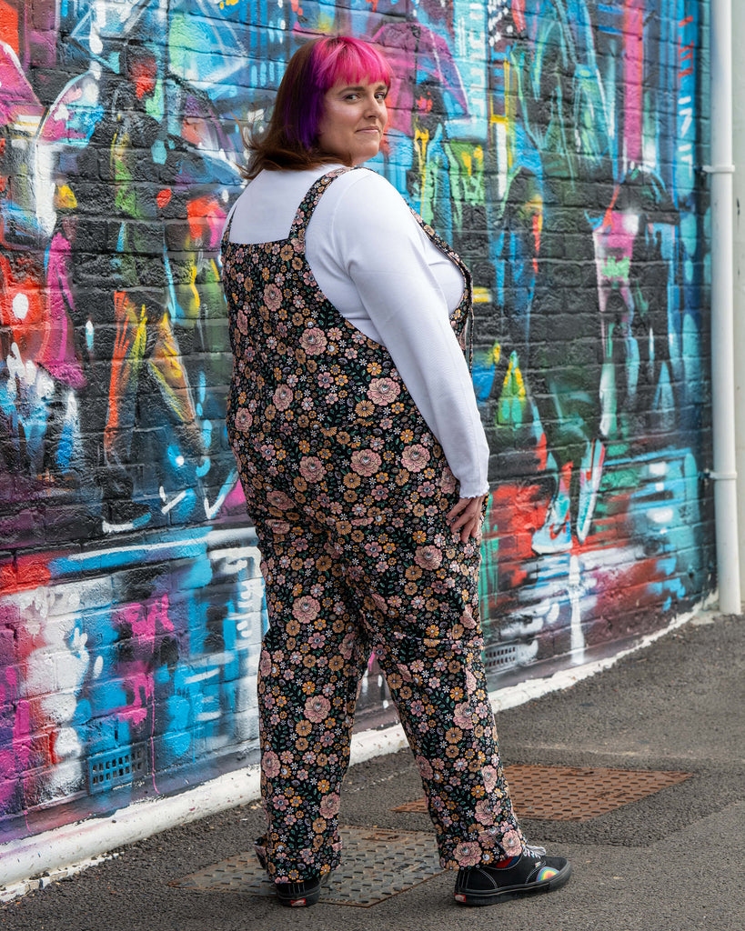 Back view of Chloe modelling the Eye Spy Floral Stretch Twill Dungarees, highlighting the all-over floral, skull, and eye print design.