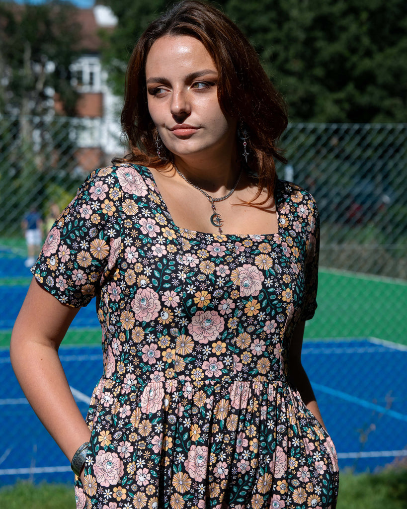 Woman wearing a floral dress standing outdoors with a blurred background
