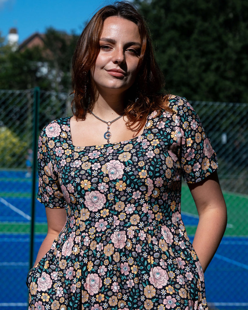 Woman wearing a floral dress standing on a tennis court