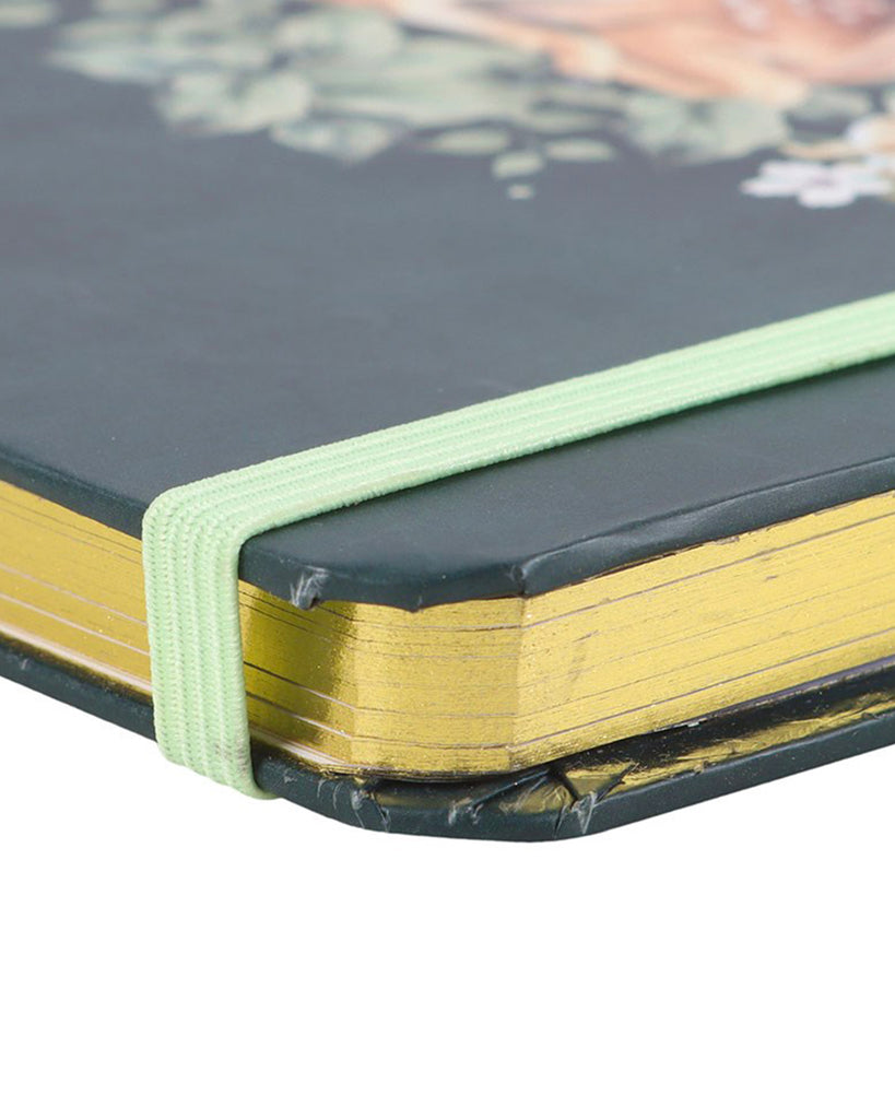 A5 notebook with a forest green cover showcasing a delicate fawn surrounded by foliage, flowers, and a crescent moon. Finished with gold-edged pages and a green elastic closure.