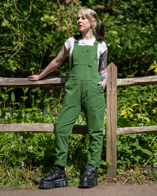 Full body shot of the Forest Green Stretch Twill Dungarees worn with a white T-shirt and black platform boots in a woodland setting.