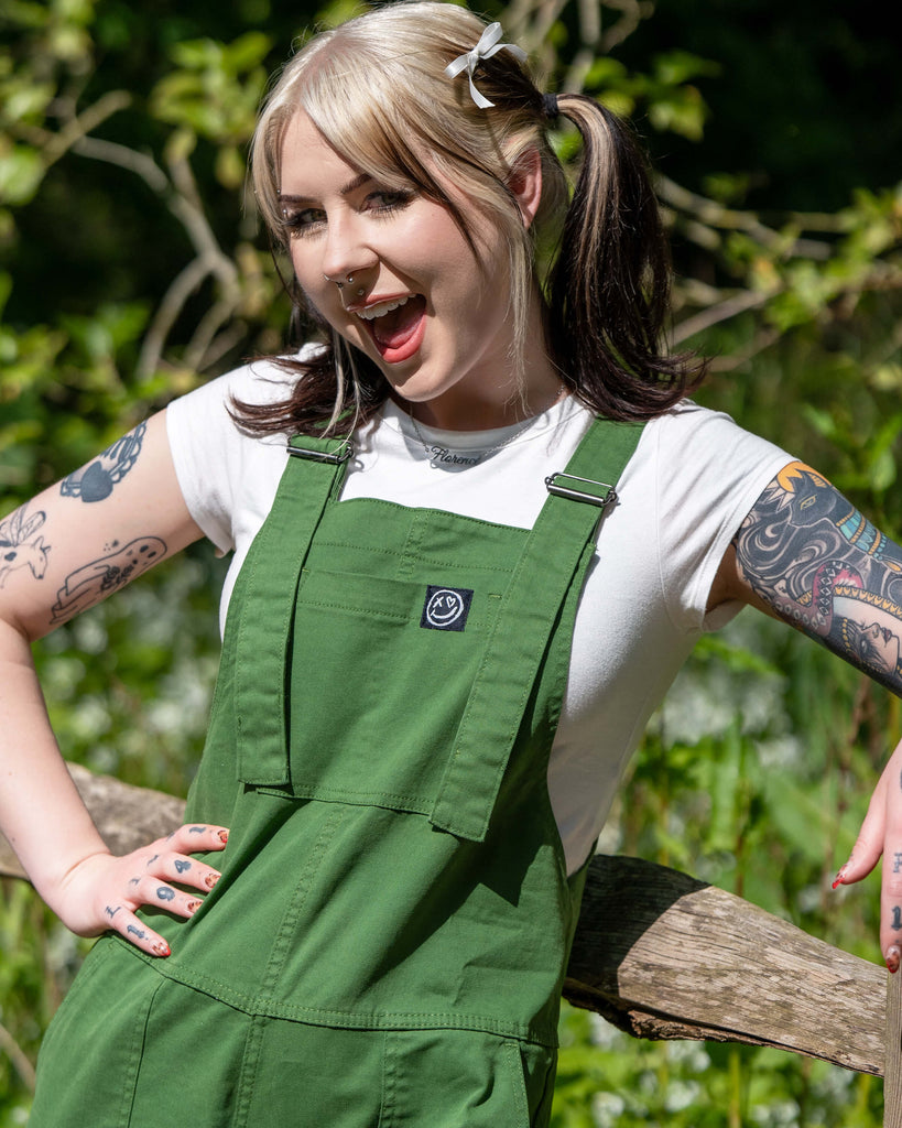 Close-up of the Rebel Romance Forest Green Dungarees’ front bib with branded patch and metal strap adjusters.